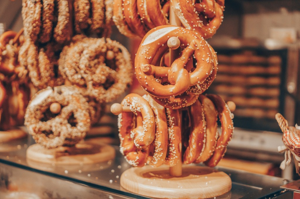 Salted pretzels displayed on wooden stands in a bakery setting.