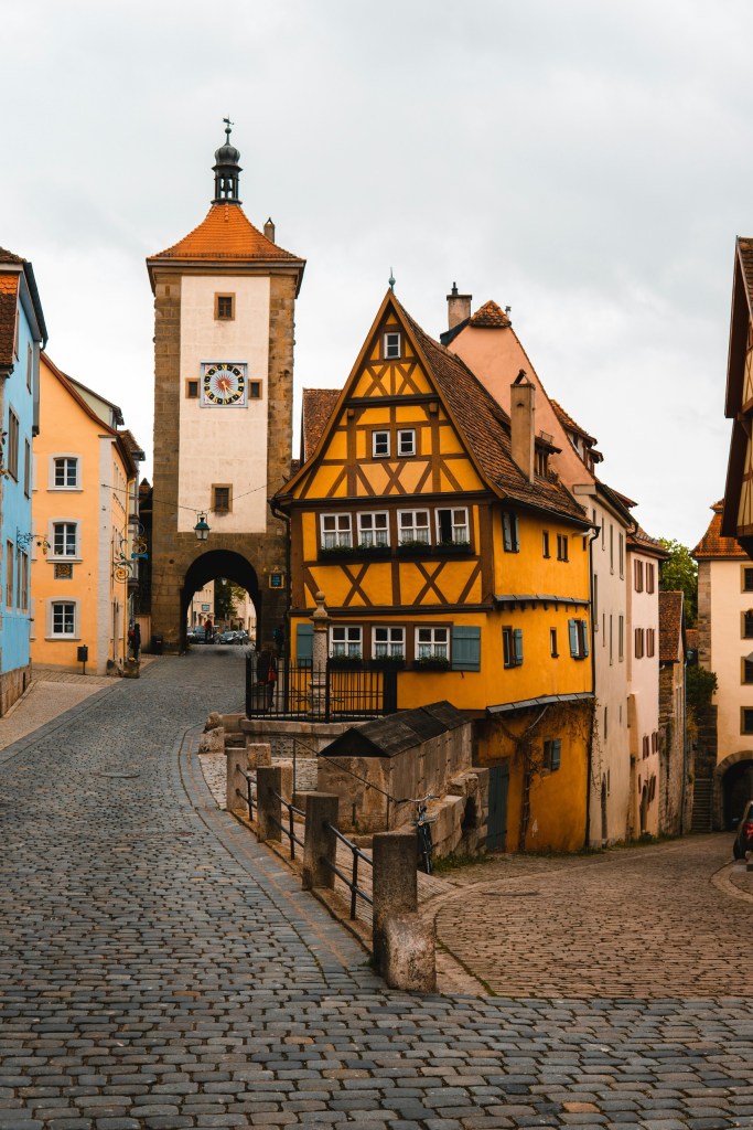 Cobblestone street with colorful historic buildings and a clock tower.