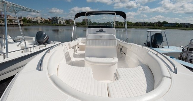 View of a white boat's bow area with seating, docked on a lake.