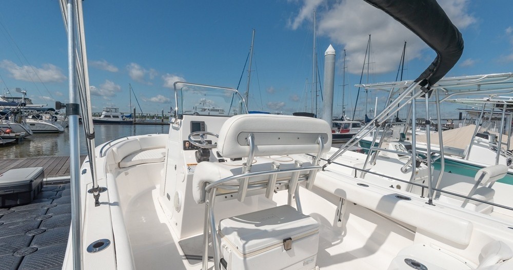 Interior of a white boat docked, with steering area and seats visible.