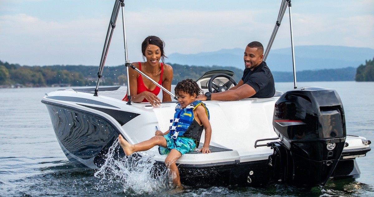 Family enjoying a boat ride on a lake, child splashing water.