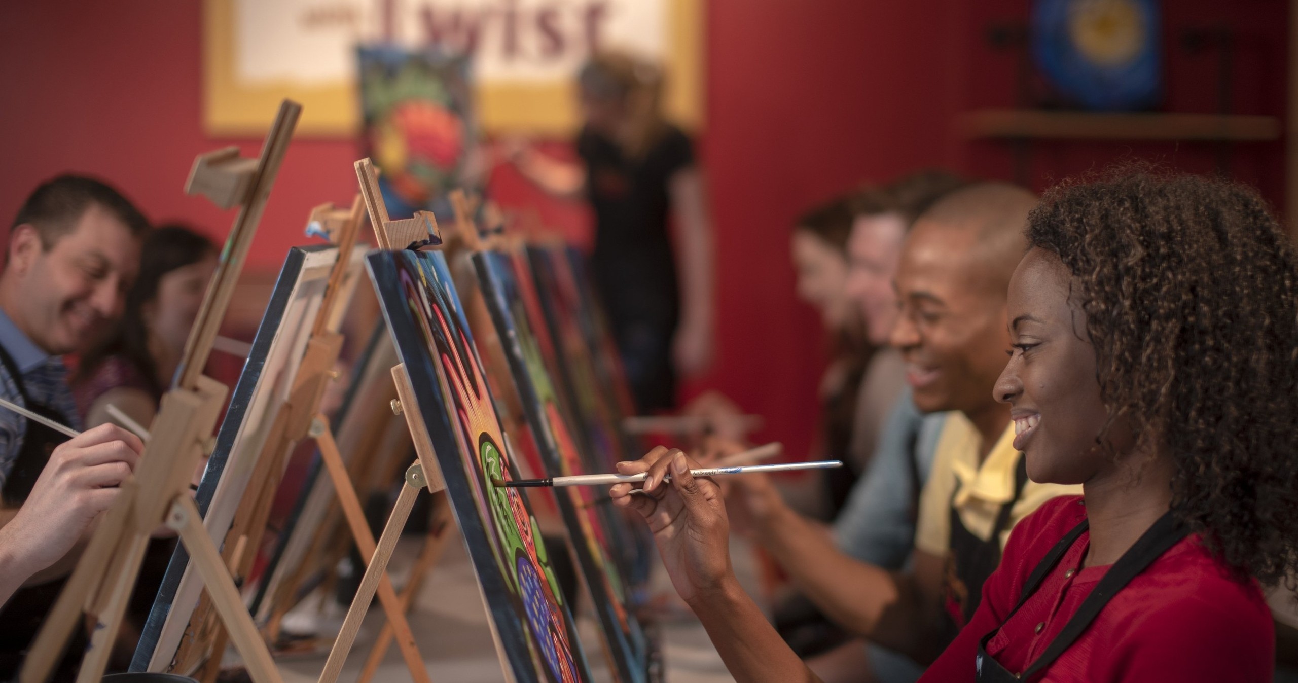 People painting on canvases at an art class with easels.