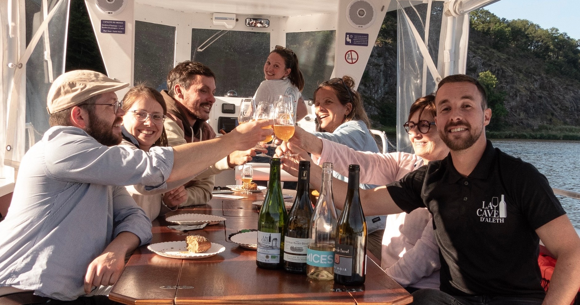 Group toasting on a boat with wine and food.