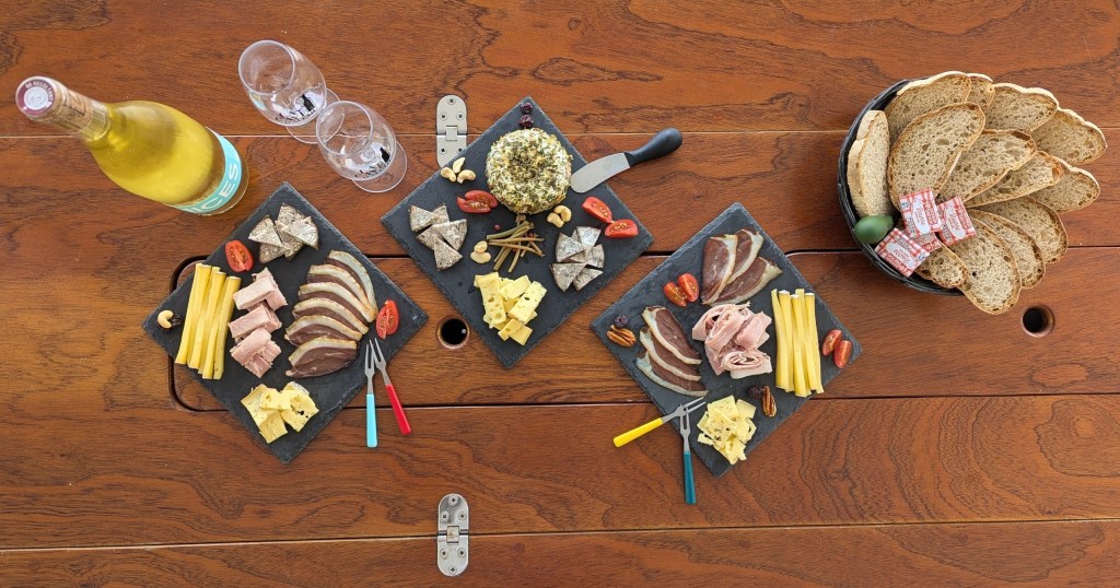 Charcuterie spread on wooden table with wine, bread, and cheese.