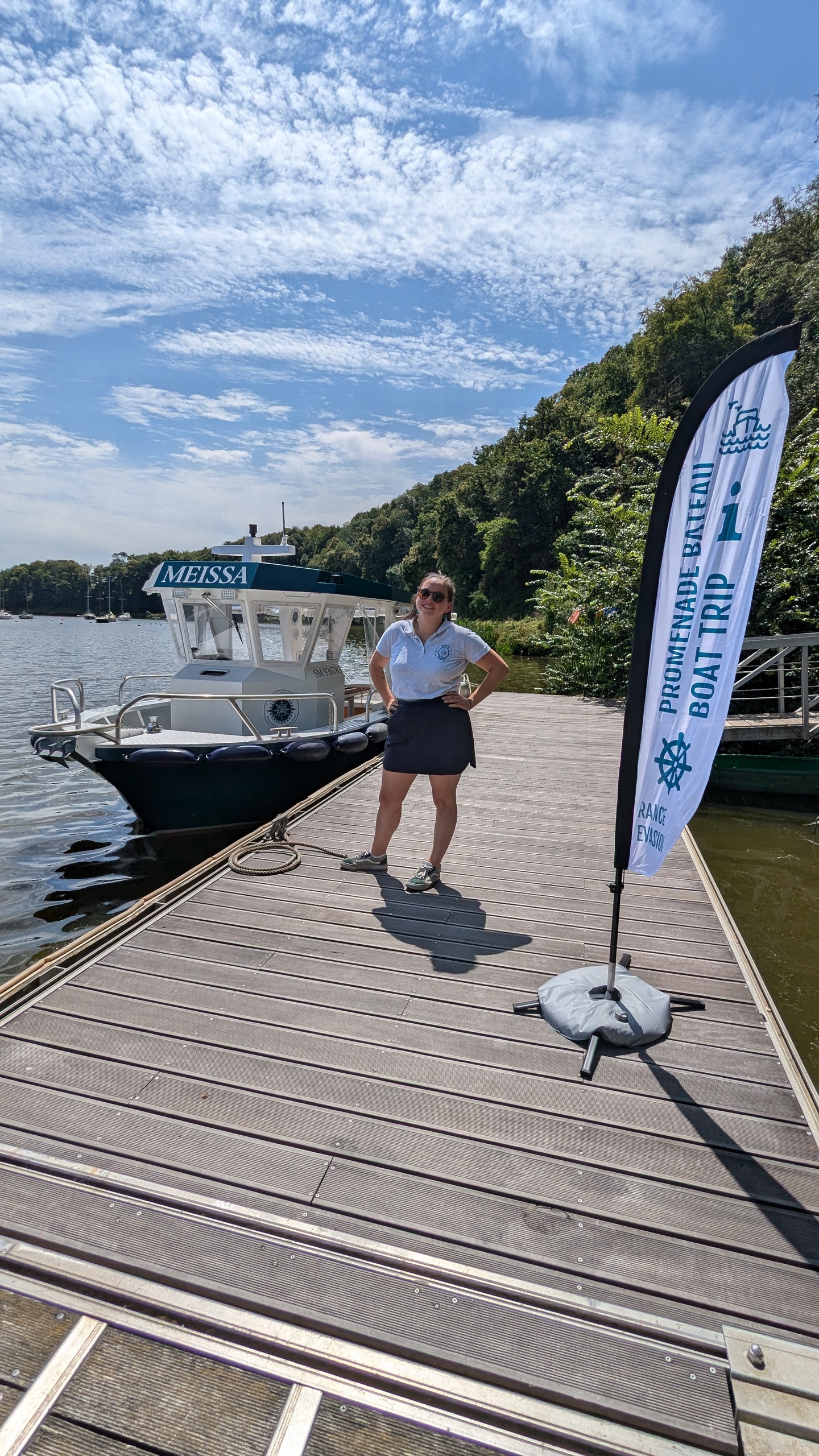 Person standing on dock beside a boat under a blue sky.