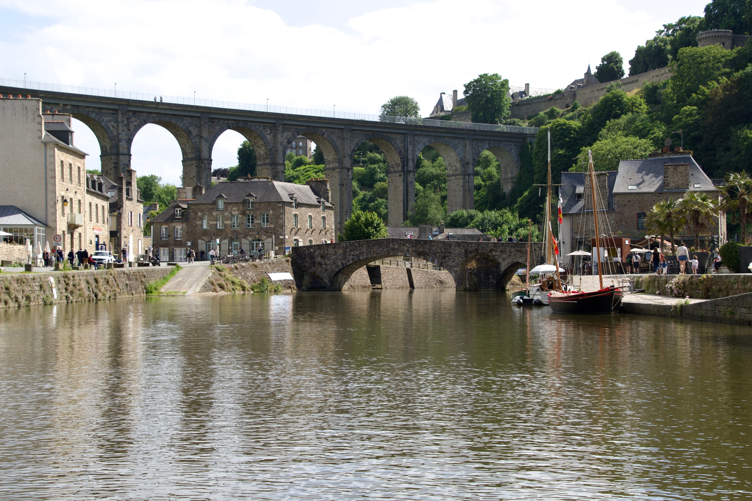 Scenic view of a river with stone bridge and viaduct in a quaint town.