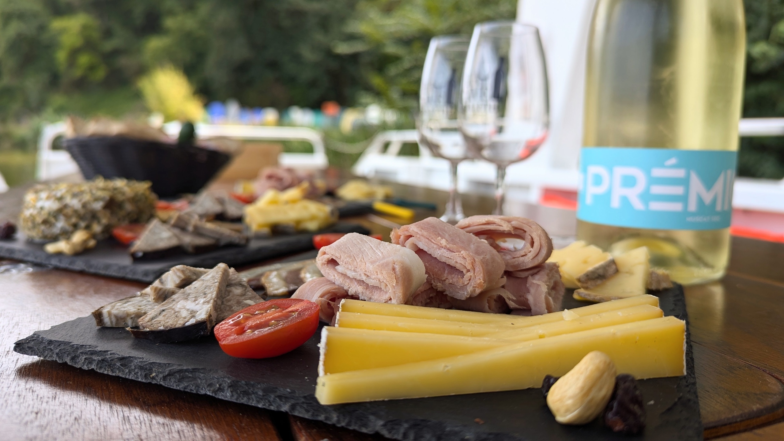 Charcuterie board with cheese, meat, wine bottle, and glasses on a table.