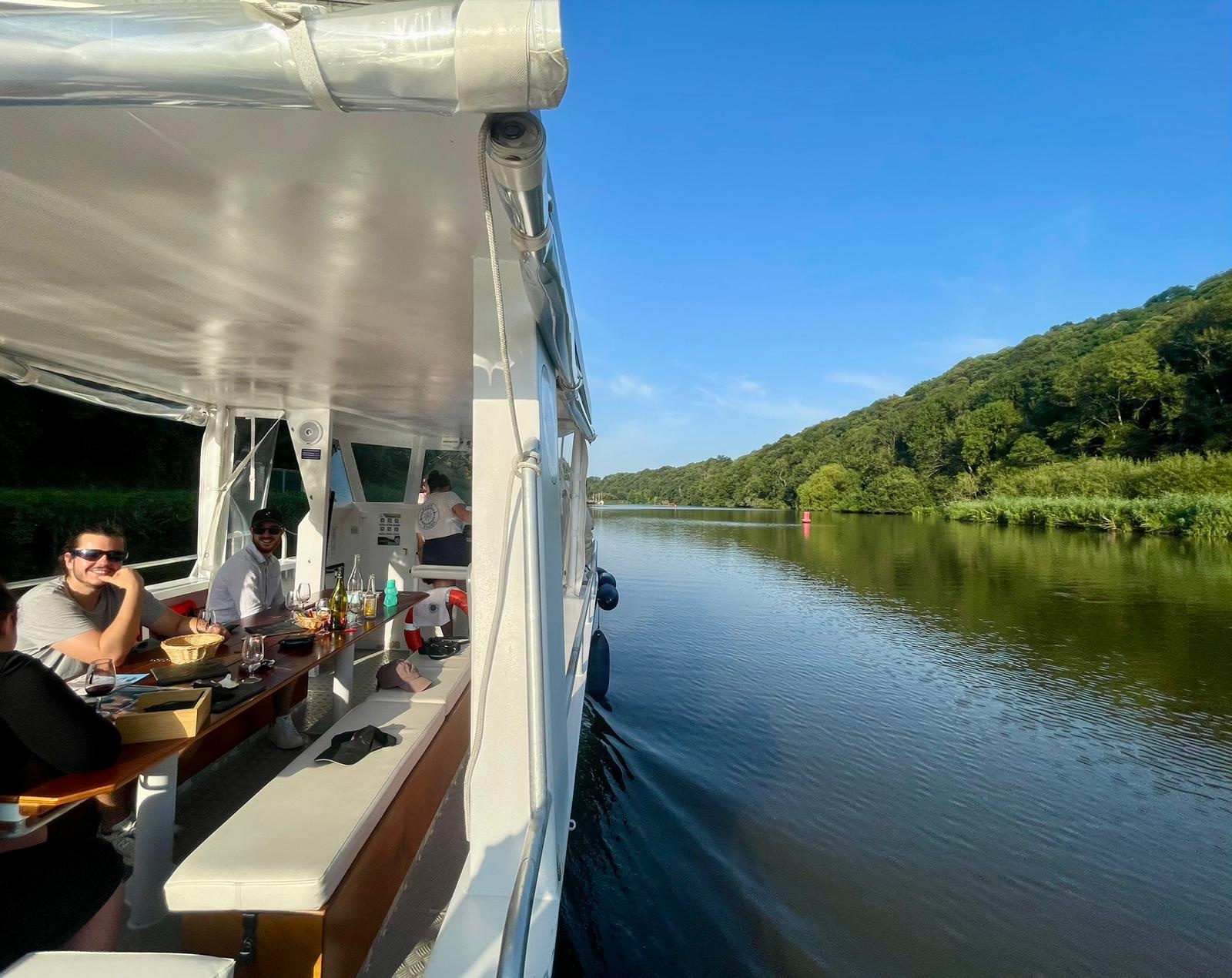 A boat with people on a calm river, surrounded by lush greenery.