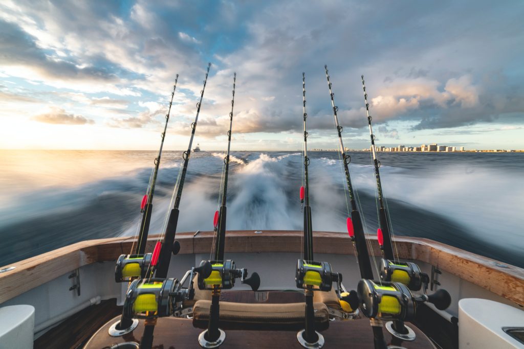 Fishing rods on a boat's stern with ocean waves and a cloudy sky.