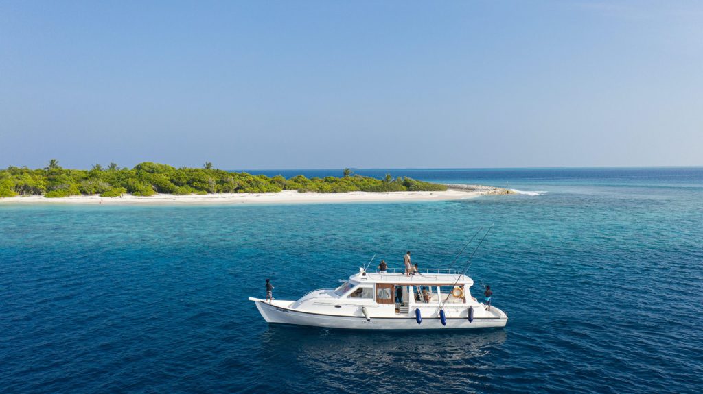 Boat sailing near a tropical island with clear blue water.