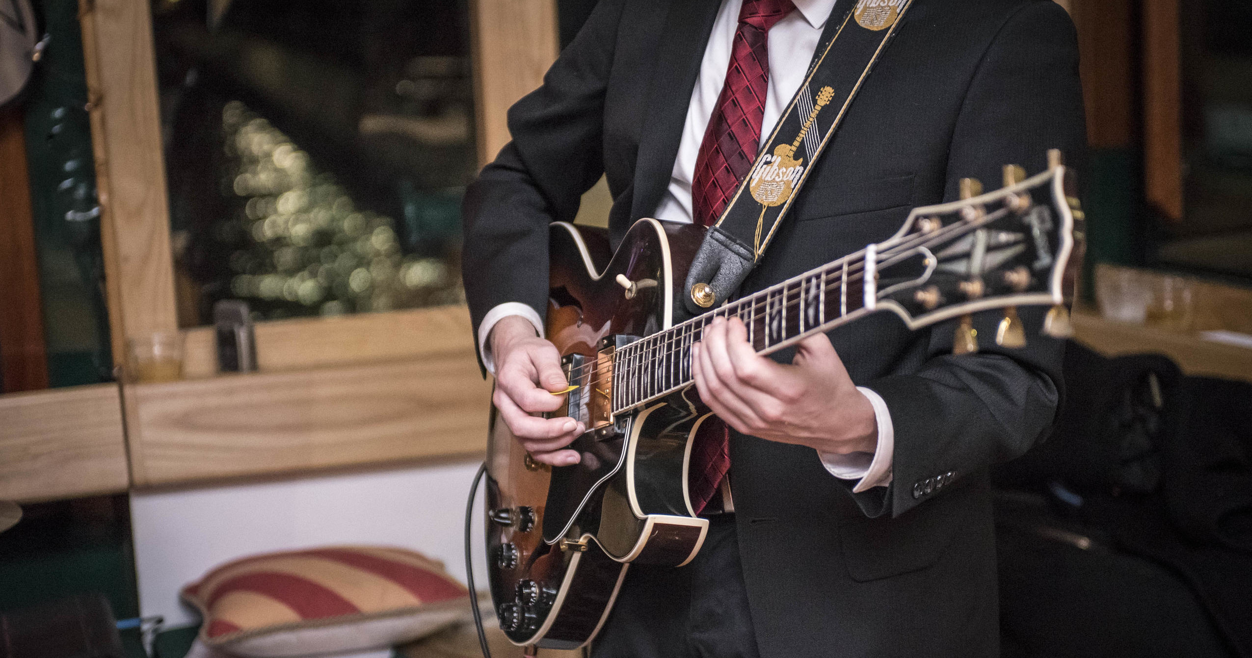 Person in suit playing electric guitar indoors.
