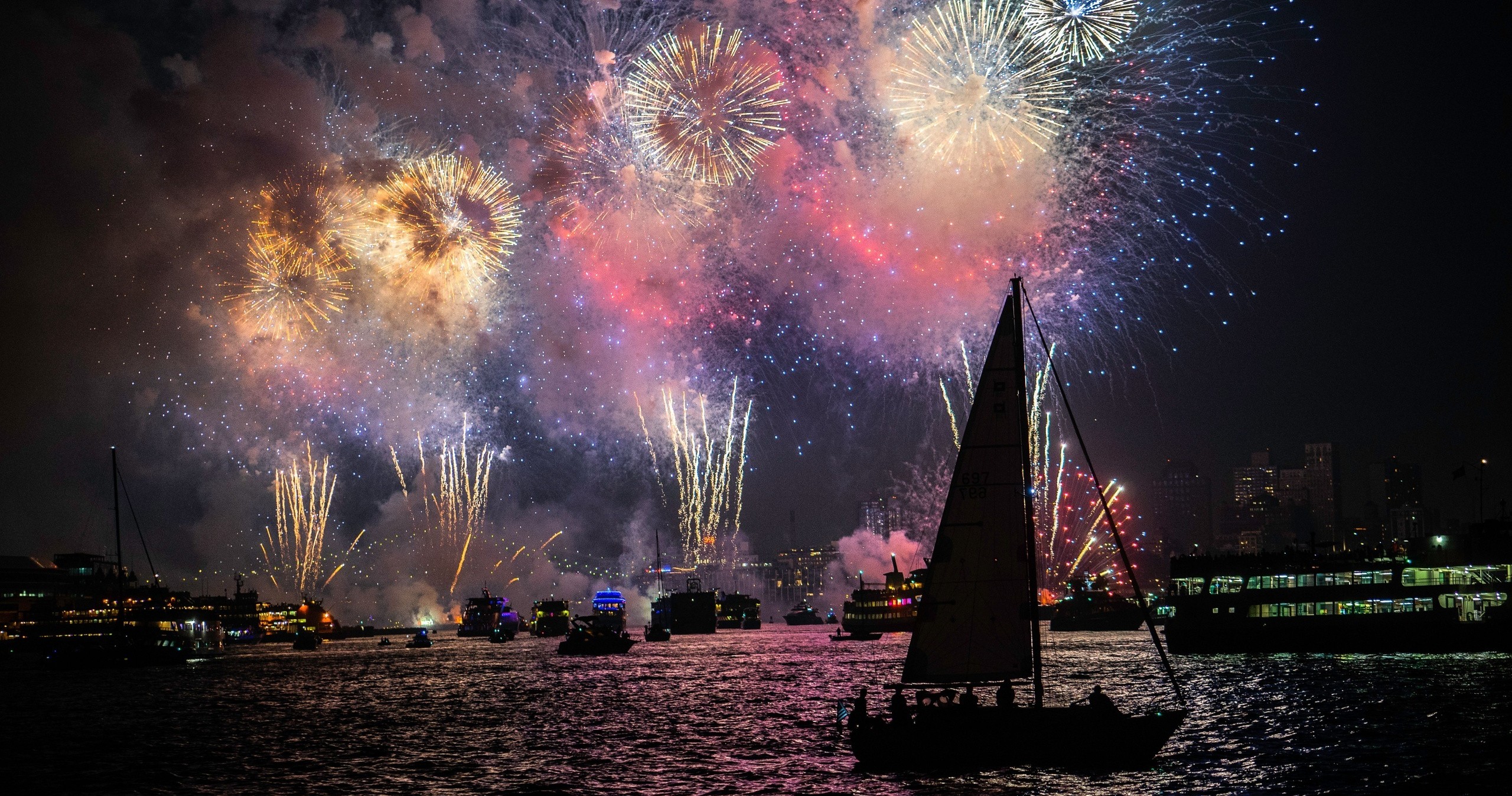 Sailboat on water with colorful fireworks in night sky