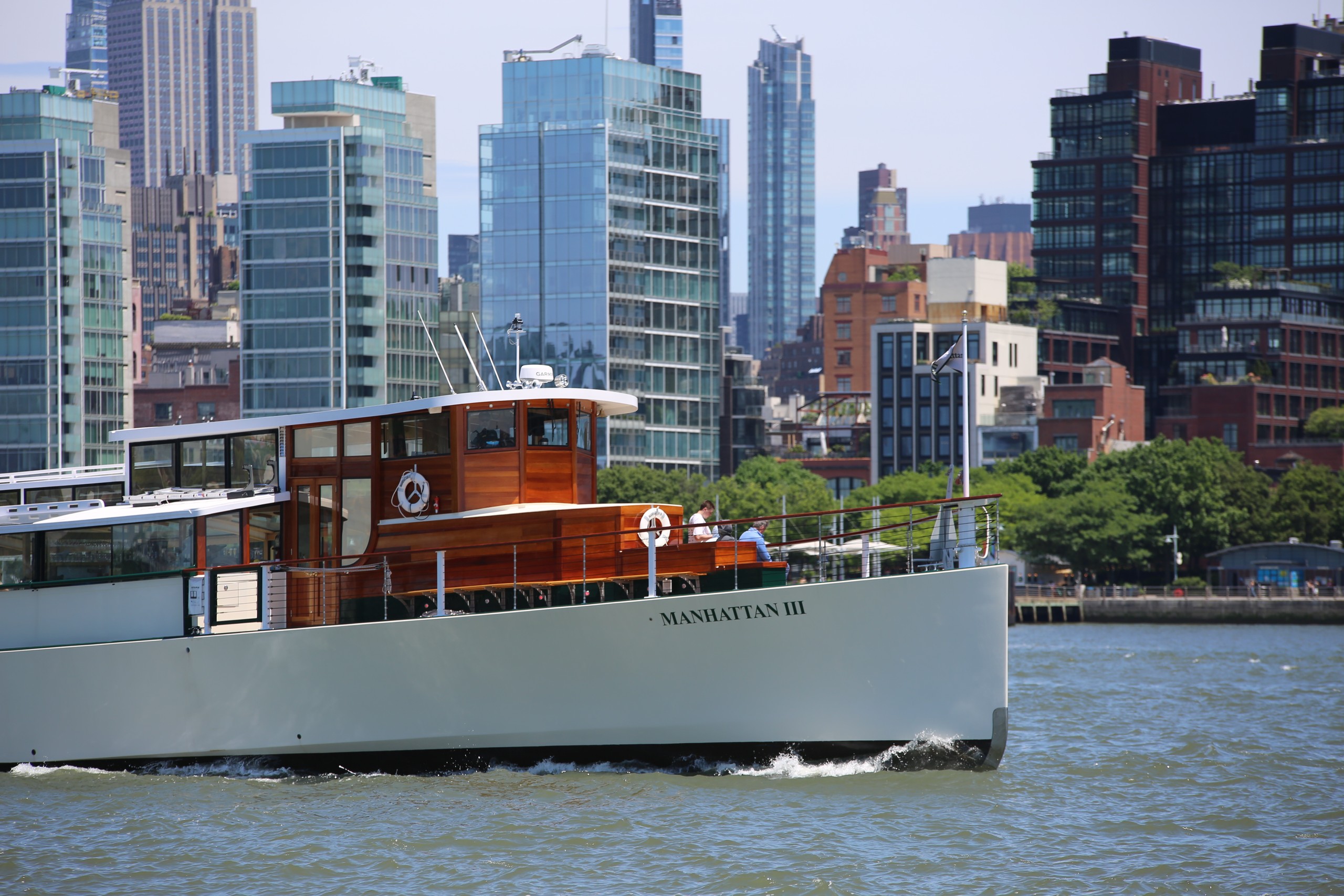 Boat on river with city skyline in the background.