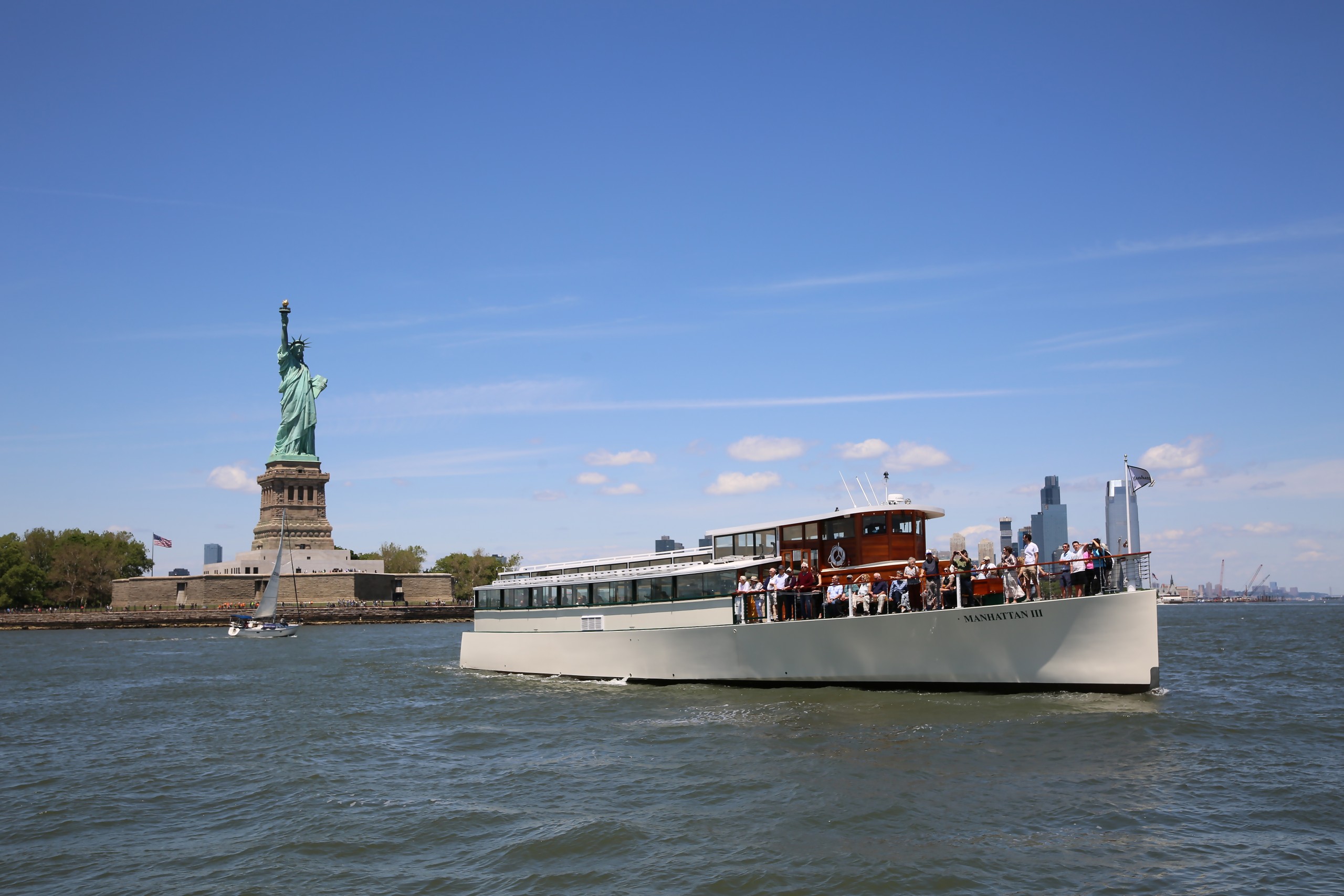 Boat near Statue of Liberty on a sunny day with clear blue sky.