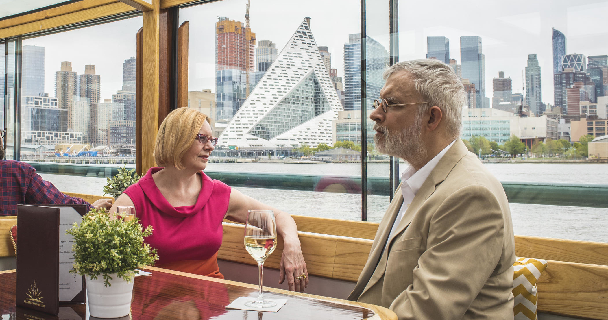 Two people sitting on a boat with city skyline in the background.