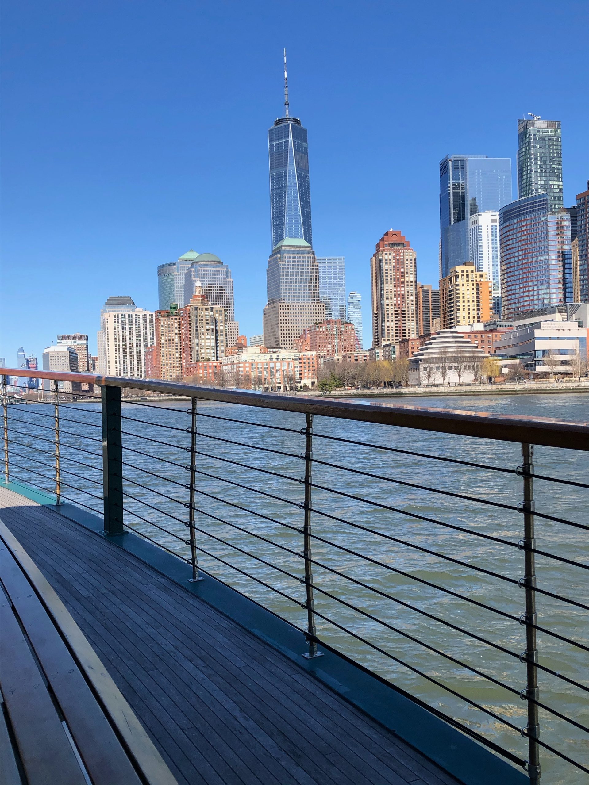 City skyline with skyscrapers viewed from a waterfront deck.