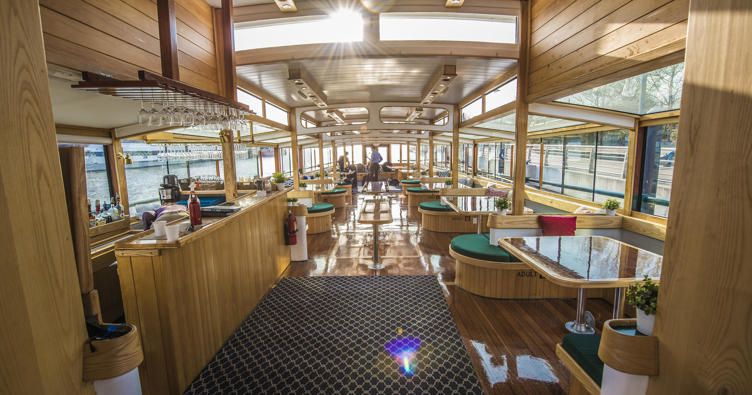 Inside view of a spacious, modern boat interior with wooden decor and large windows.