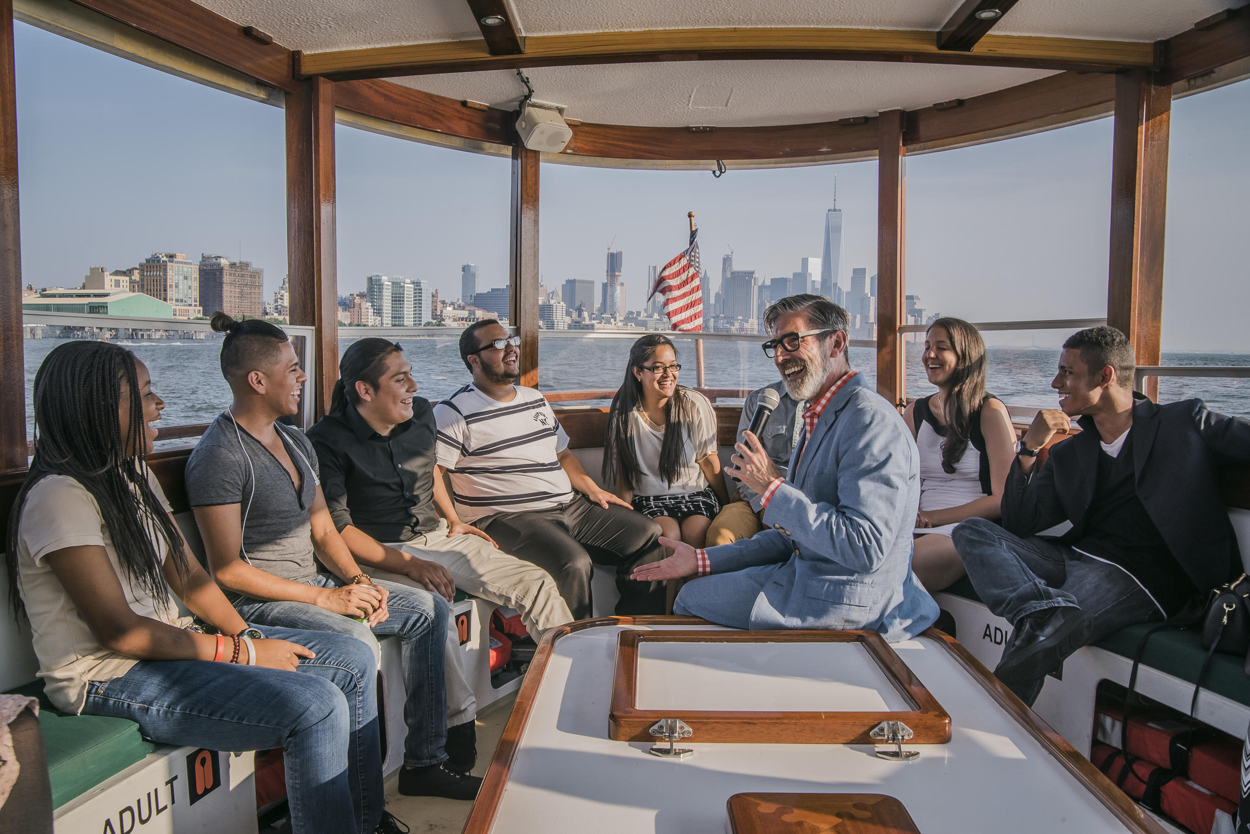 Group of people sitting on a boat with a city skyline in the background.