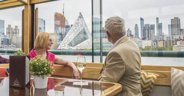 Two people dining on a boat with city skyline view.