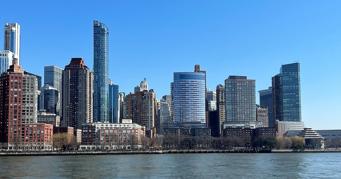 Skyline with modern skyscrapers by a waterfront on a clear day.