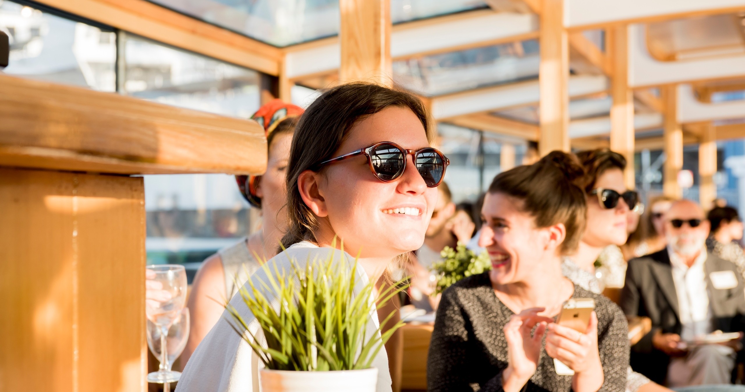 People in sunglasses and casual attire enjoying a sunny gathering indoors.