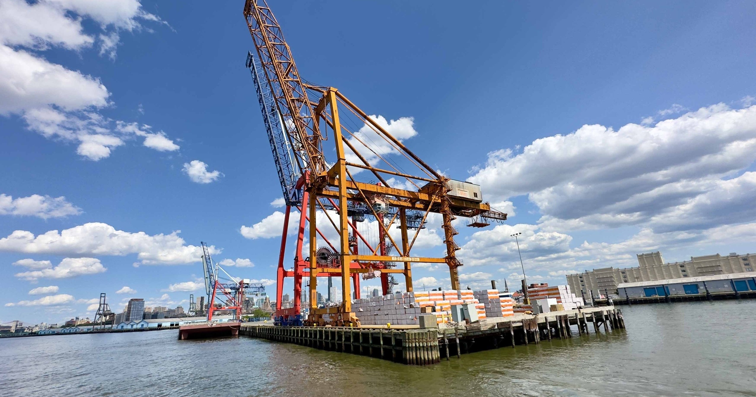 Large cranes at a harbor with a clear blue sky and scattered clouds.