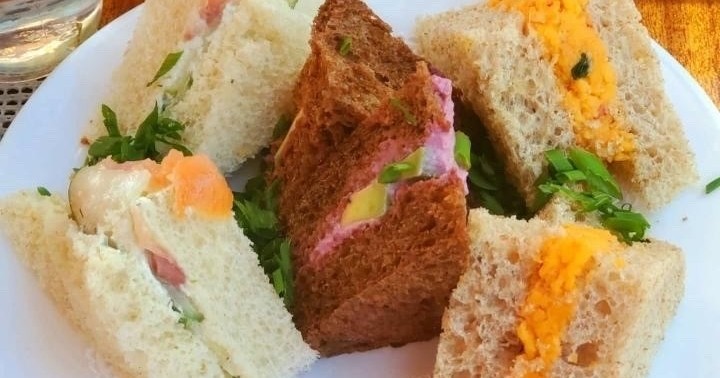 Assorted finger sandwiches on a plate with different fillings.