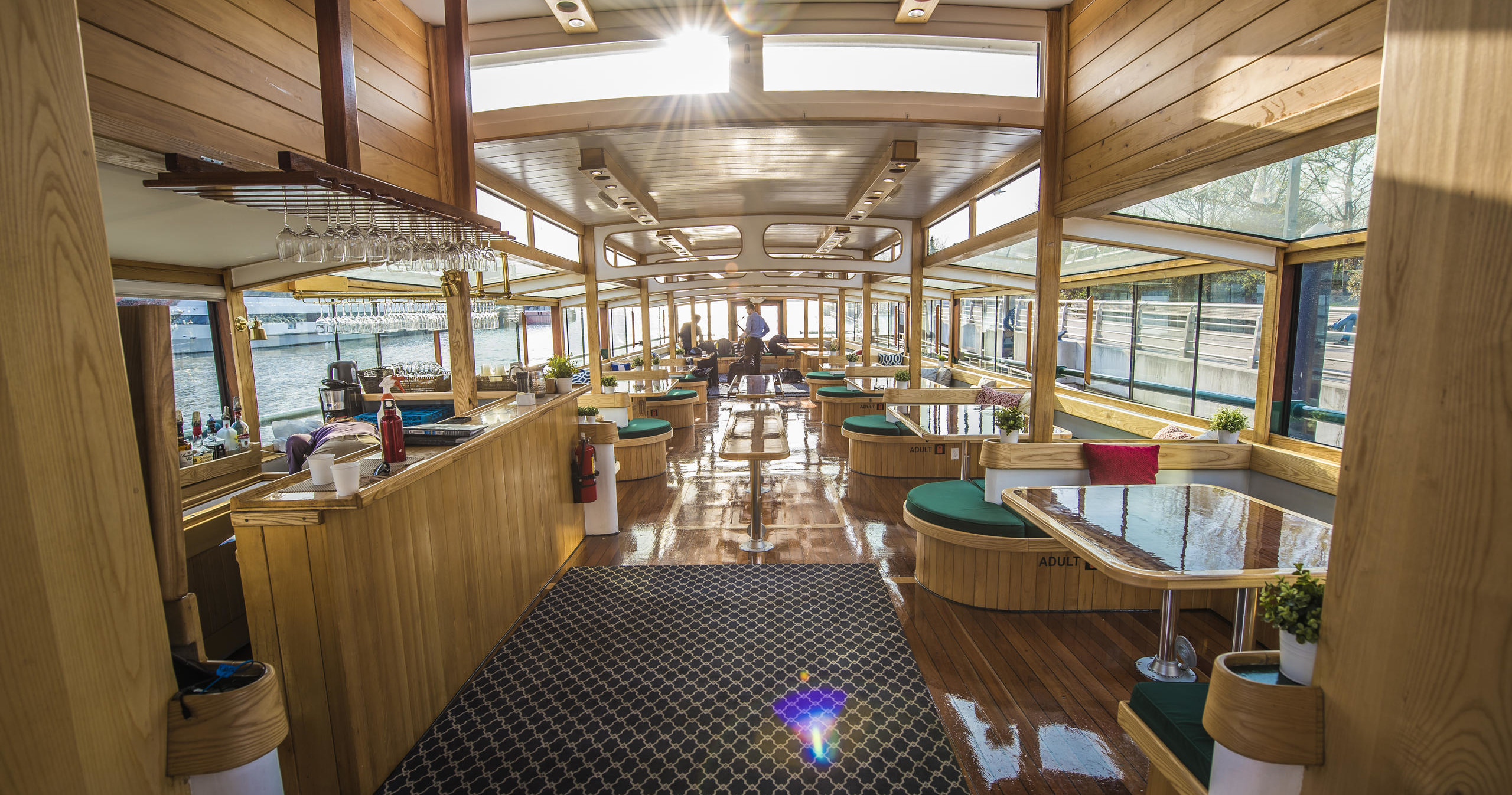 Interior of a sunny boat with wooden decor and dining tables.