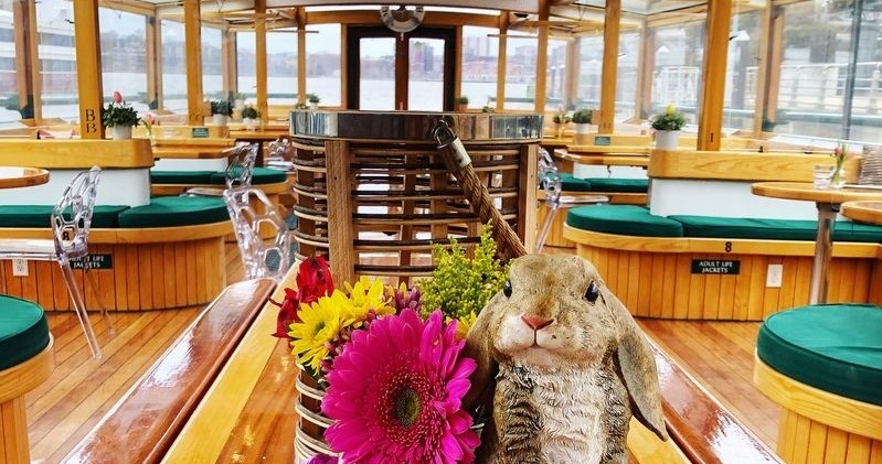 Wooden boat interior with benches, flowers, and a plush rabbit.