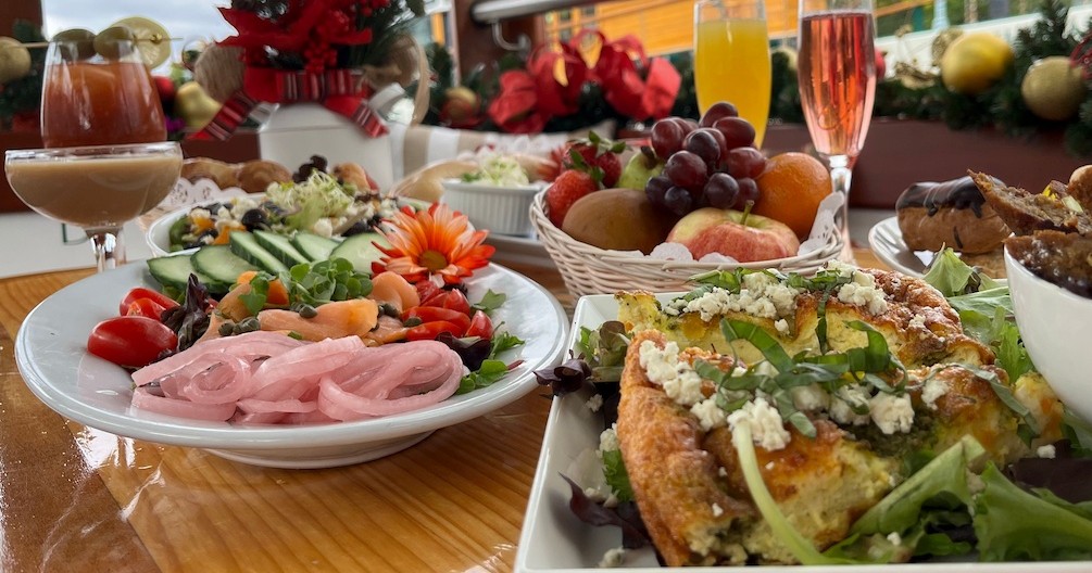 Assorted dishes on a table with salads, fruit, and drinks in a festive setting.