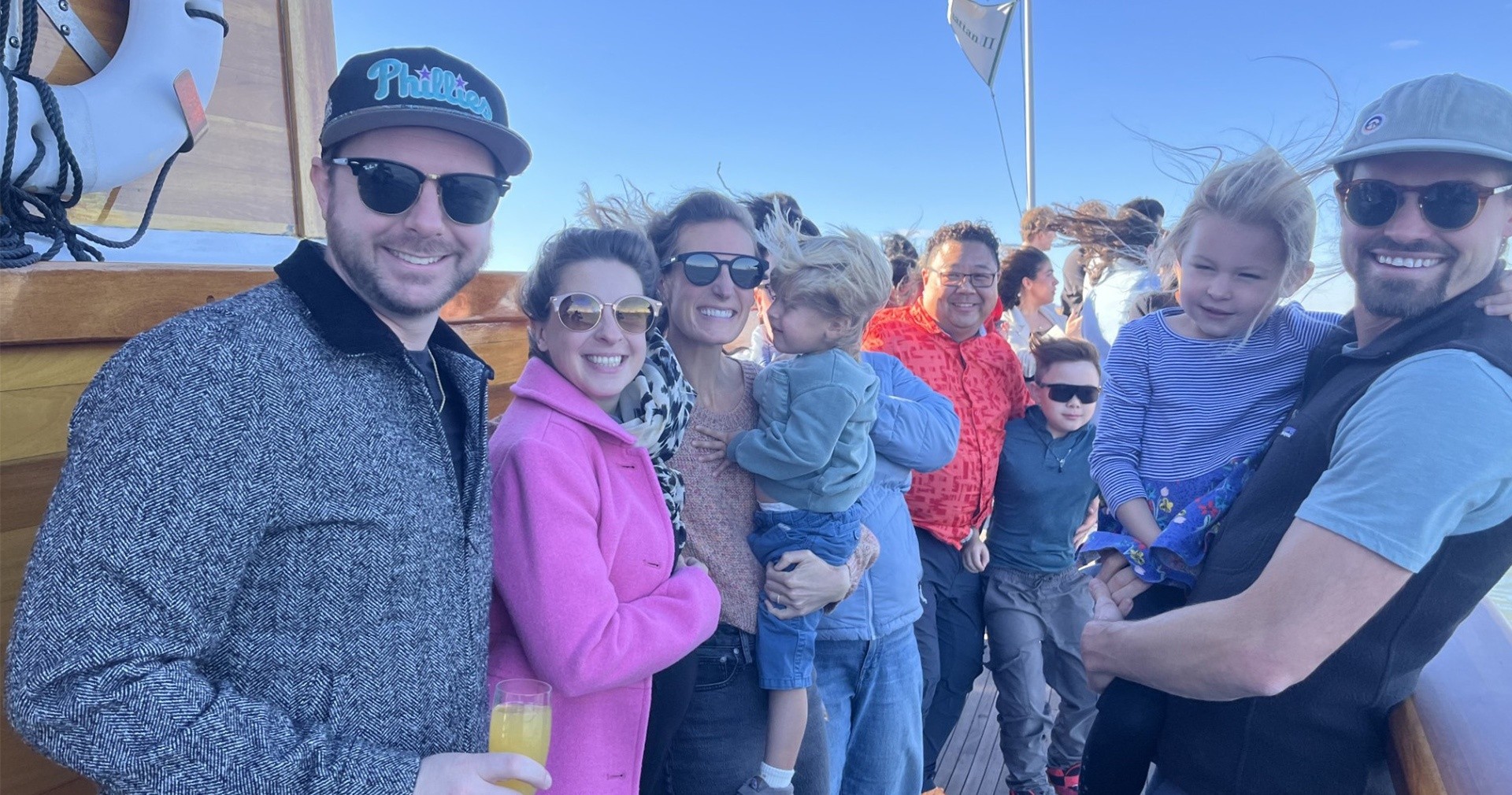 Group of people smiling on a boat, sunny day.