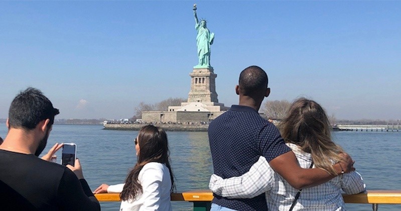 People on a boat view the Statue of Liberty across the water.