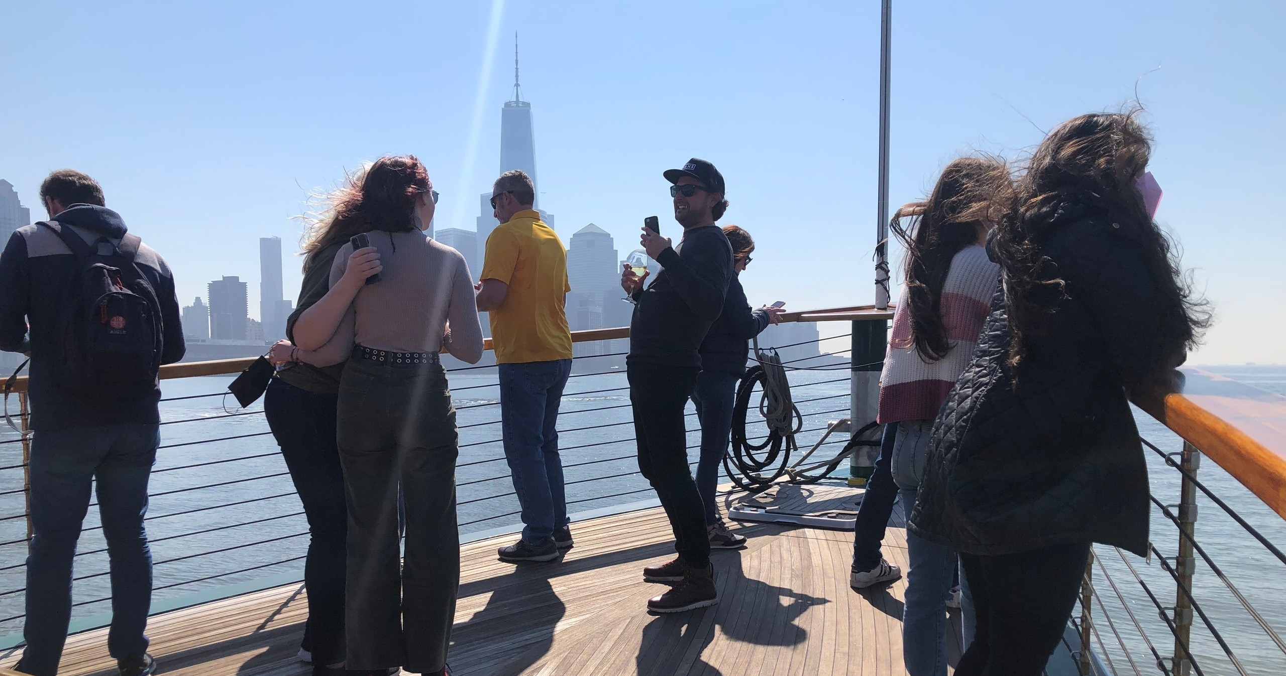 People on a boat deck with city skyline background on a sunny day.