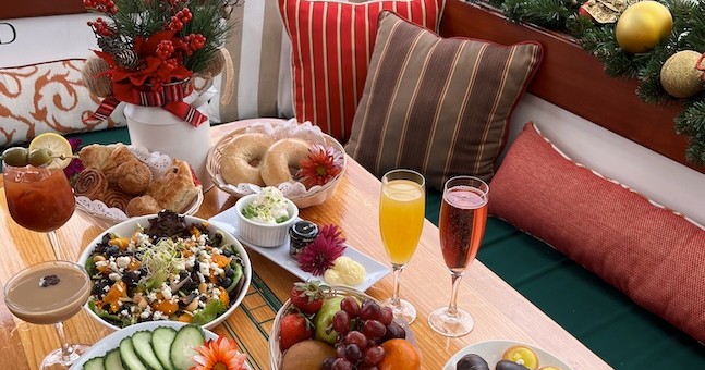 Festive brunch setup with salads, fruits, drinks, and rolls on a decorated table.
