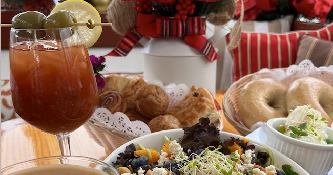 Brunch spread with a salad, pastries, and a cocktail on a table.