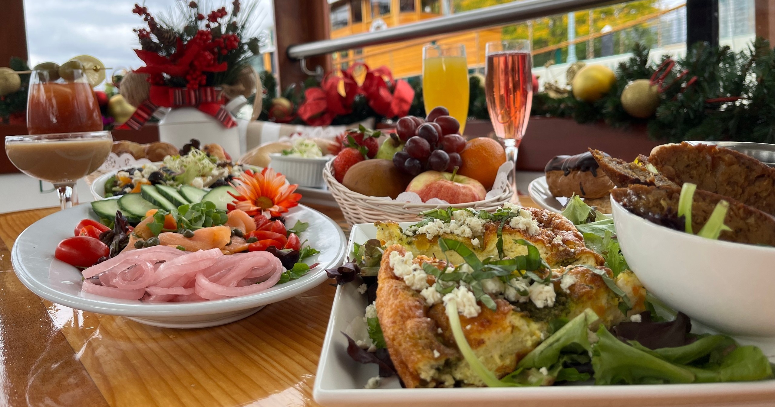 Table with assorted dishes, including salad, fruits, and drinks, decorated for a festive occasion.