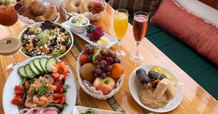 Assorted brunch items on a table, including fruit, salads, pastries, and drinks.