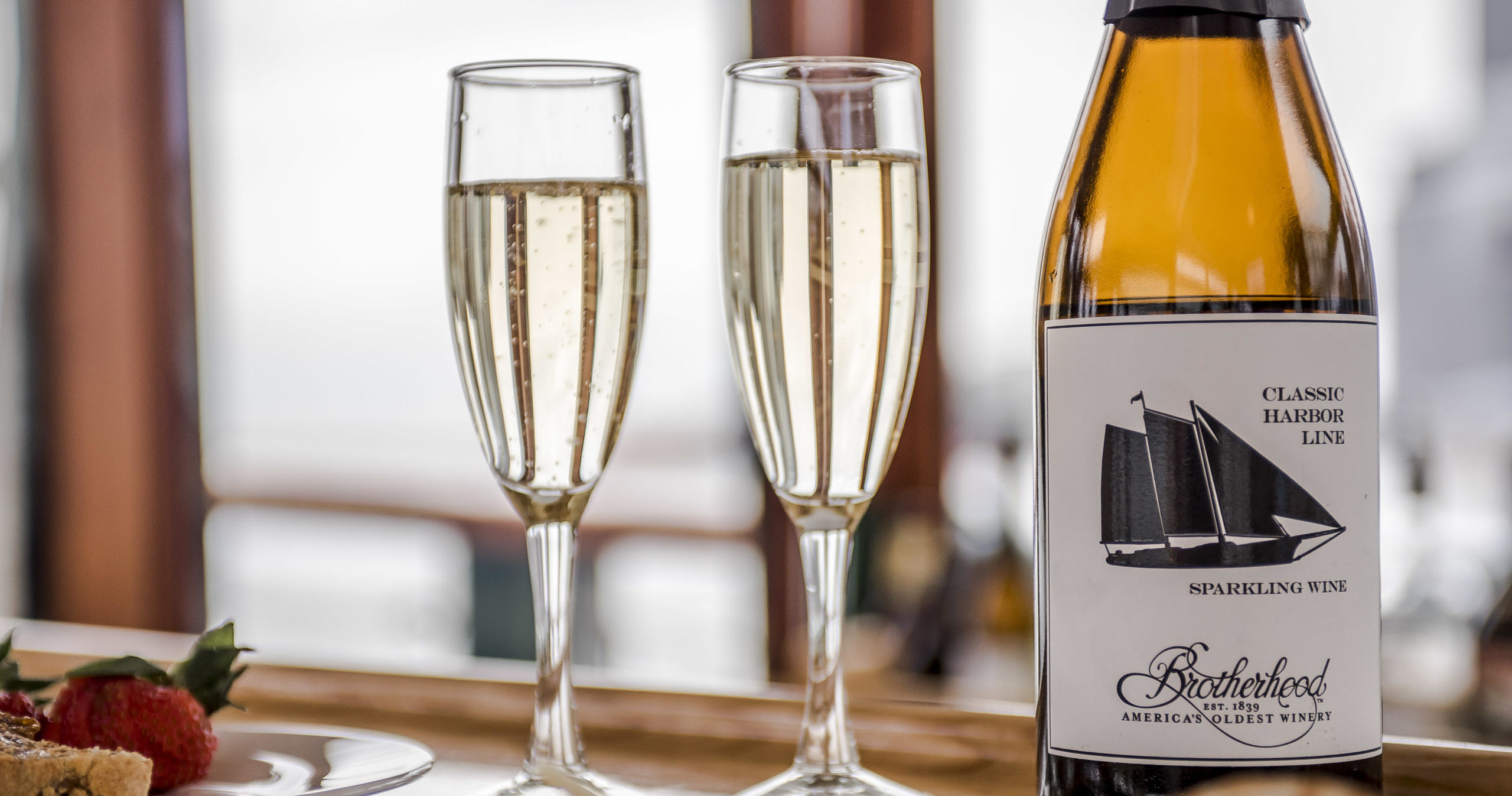 Two champagne flutes and a wine bottle on a wooden table.