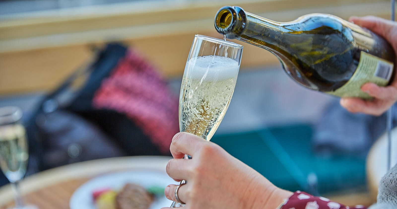 Person pouring champagne into a flute glass.
