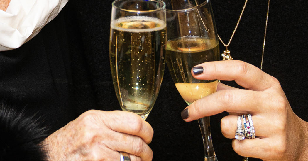 Two people clinking champagne glasses in a celebratory toast.