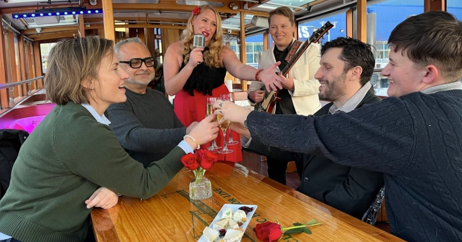 People toasting at a table on a boat, with a singer and guitarist performing.
