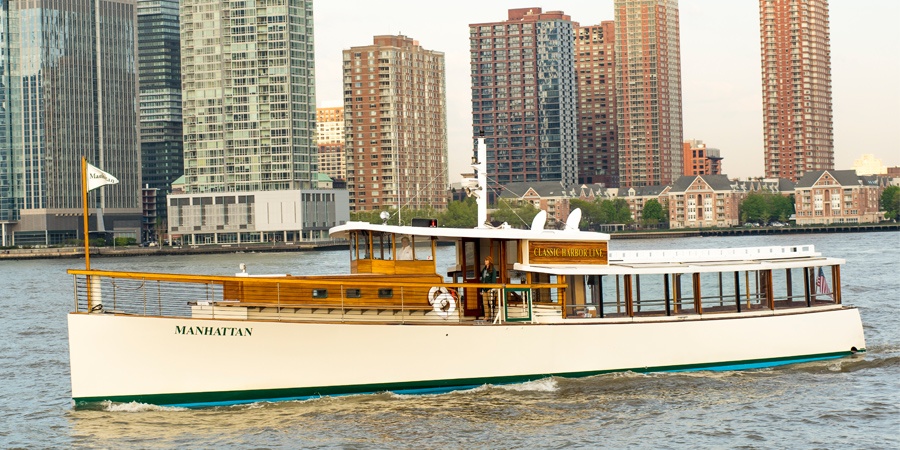 White yacht cruising on a river with a city skyline in the background.