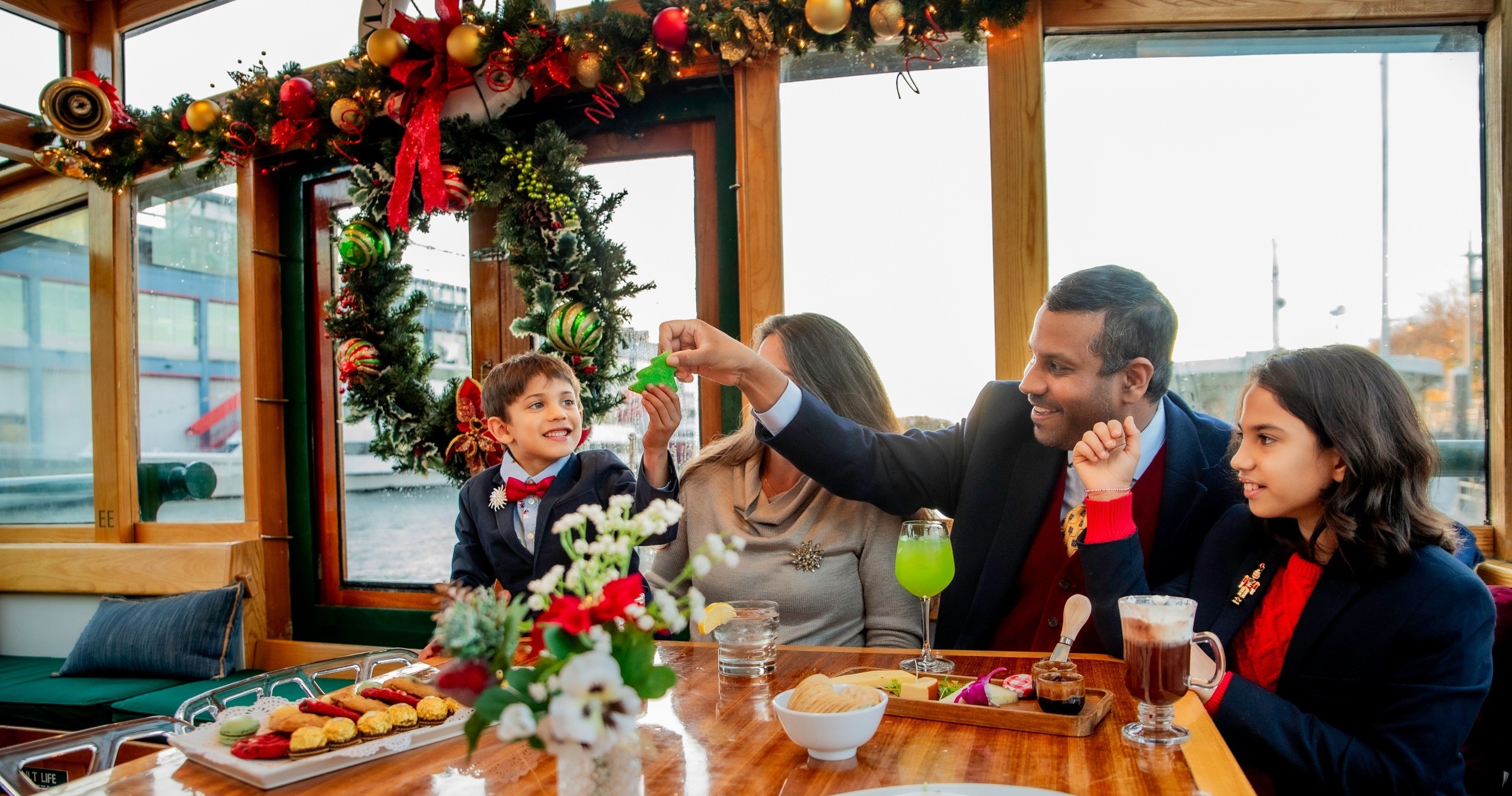 Family on a decorated boat enjoying drinks and snacks.