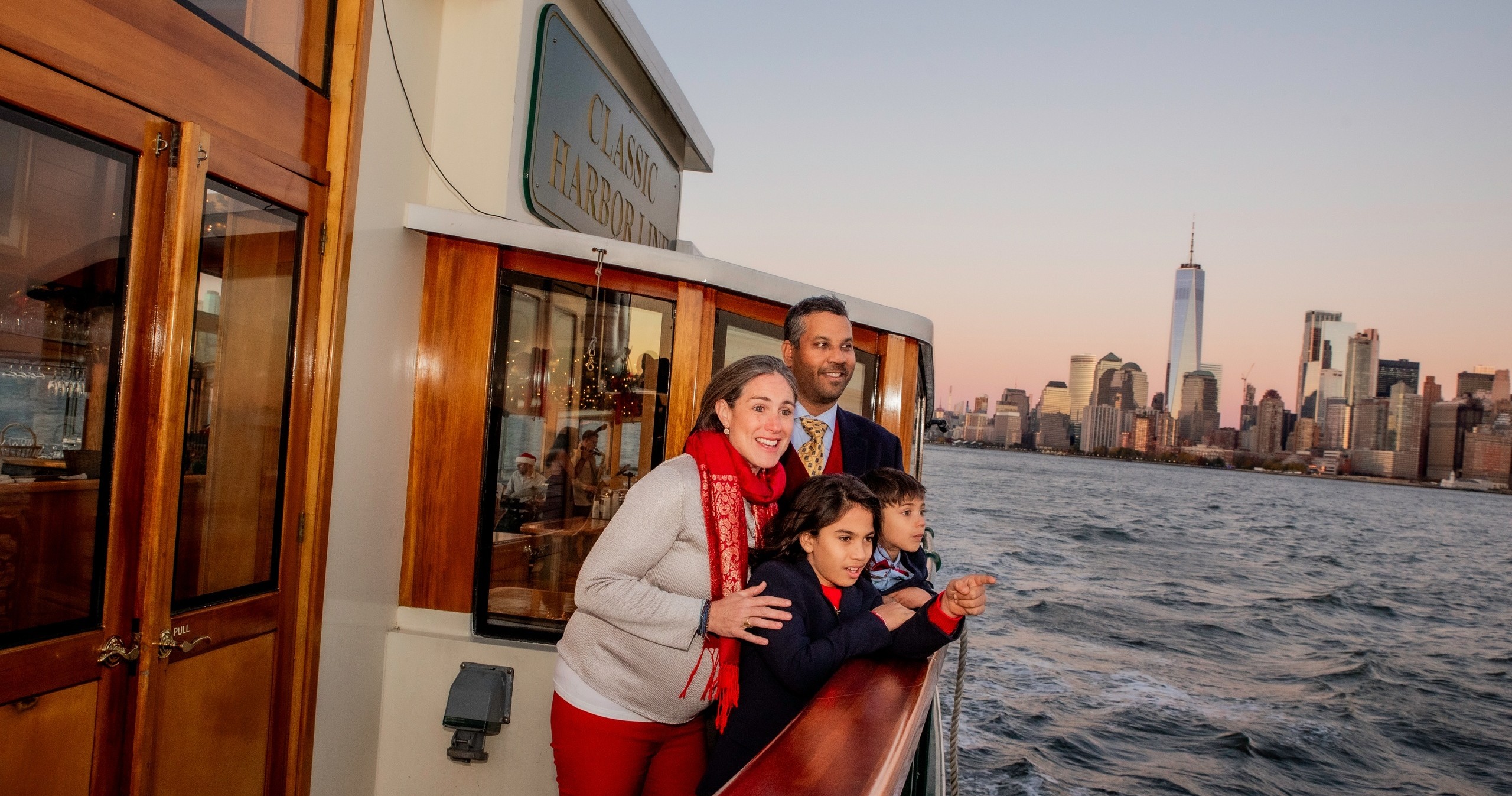 Family on a boat, city skyline with tall buildings at sunset.