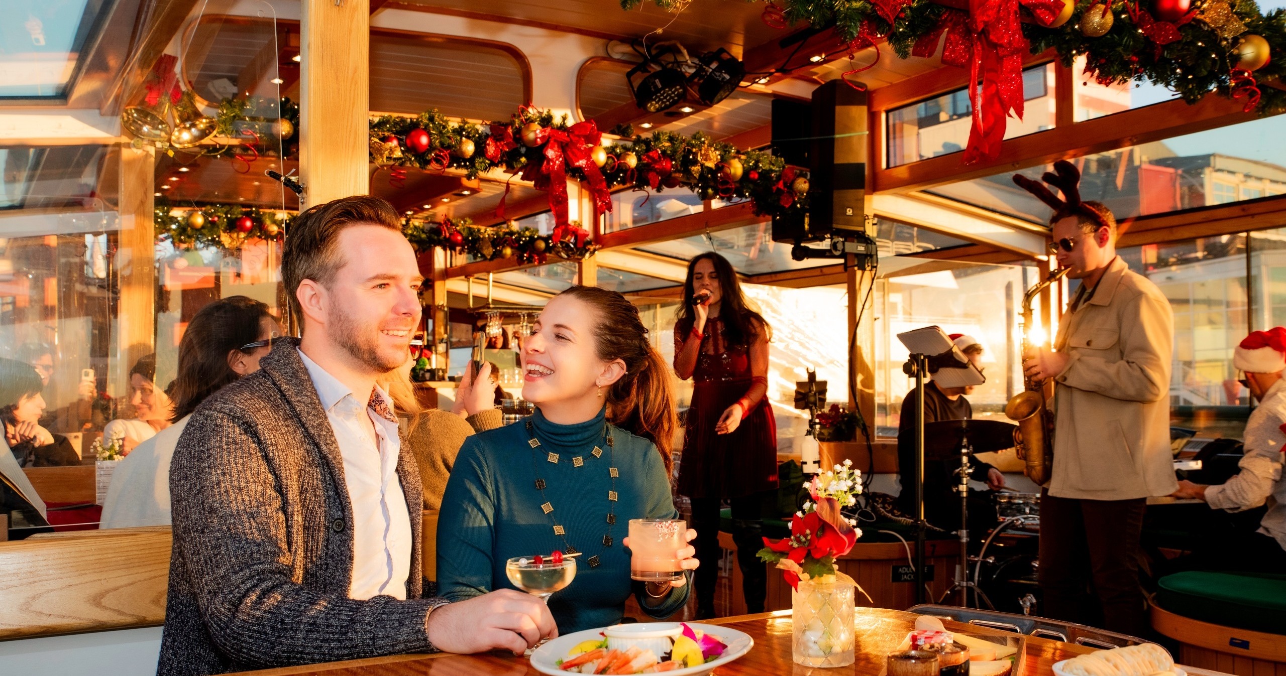 Couple dining on a festive boat with music and holiday decorations.