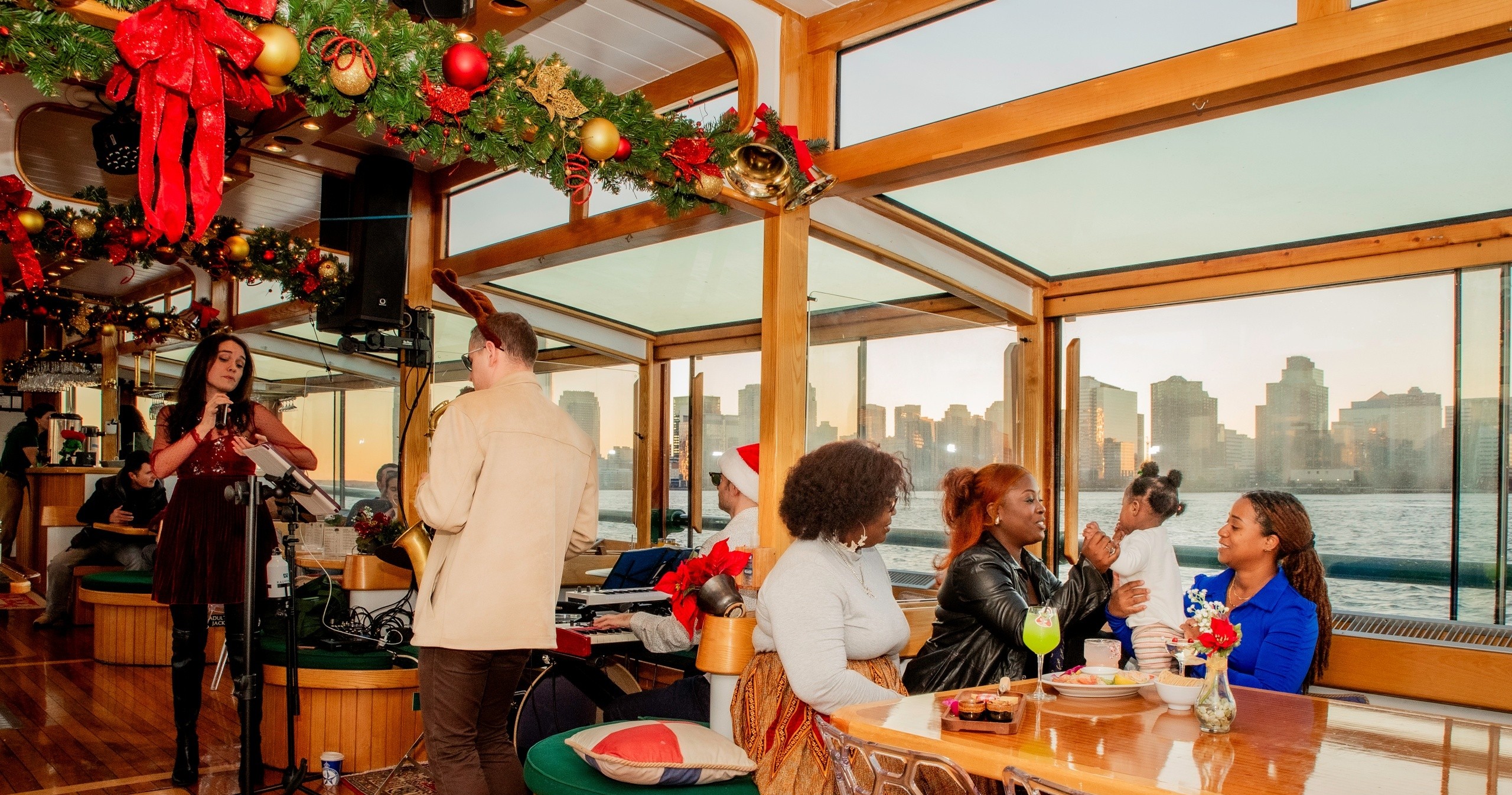Festive boat interior with musicians and people dining, cityscape view.