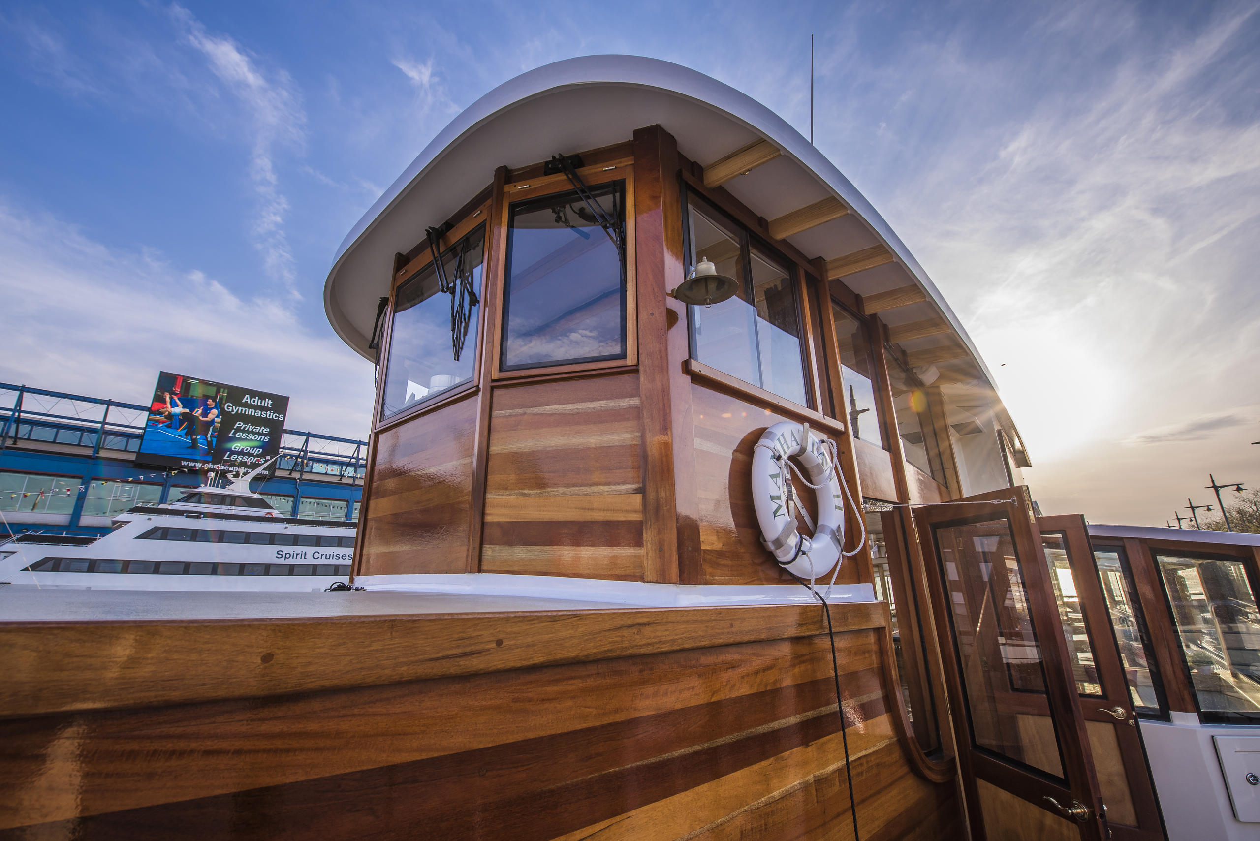Wooden boat cabin with a lifebuoy and open door, under a cloudy sky.
