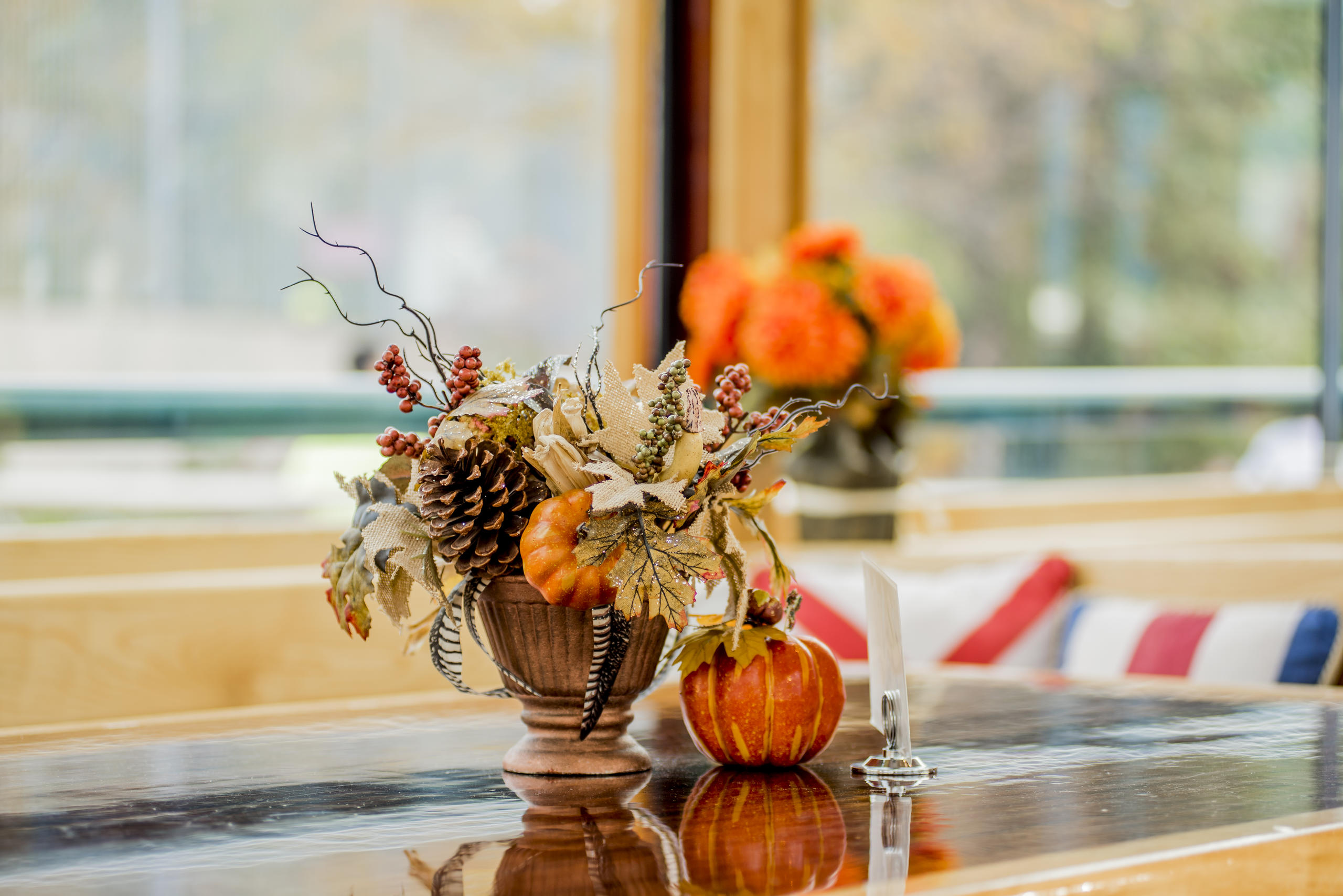 Autumn-themed table with pinecones, leaves, and pumpkins on a reflective surface.