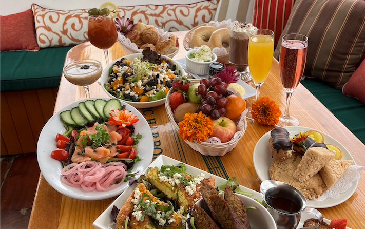 Table with various breakfast dishes, fruits, and beverages.