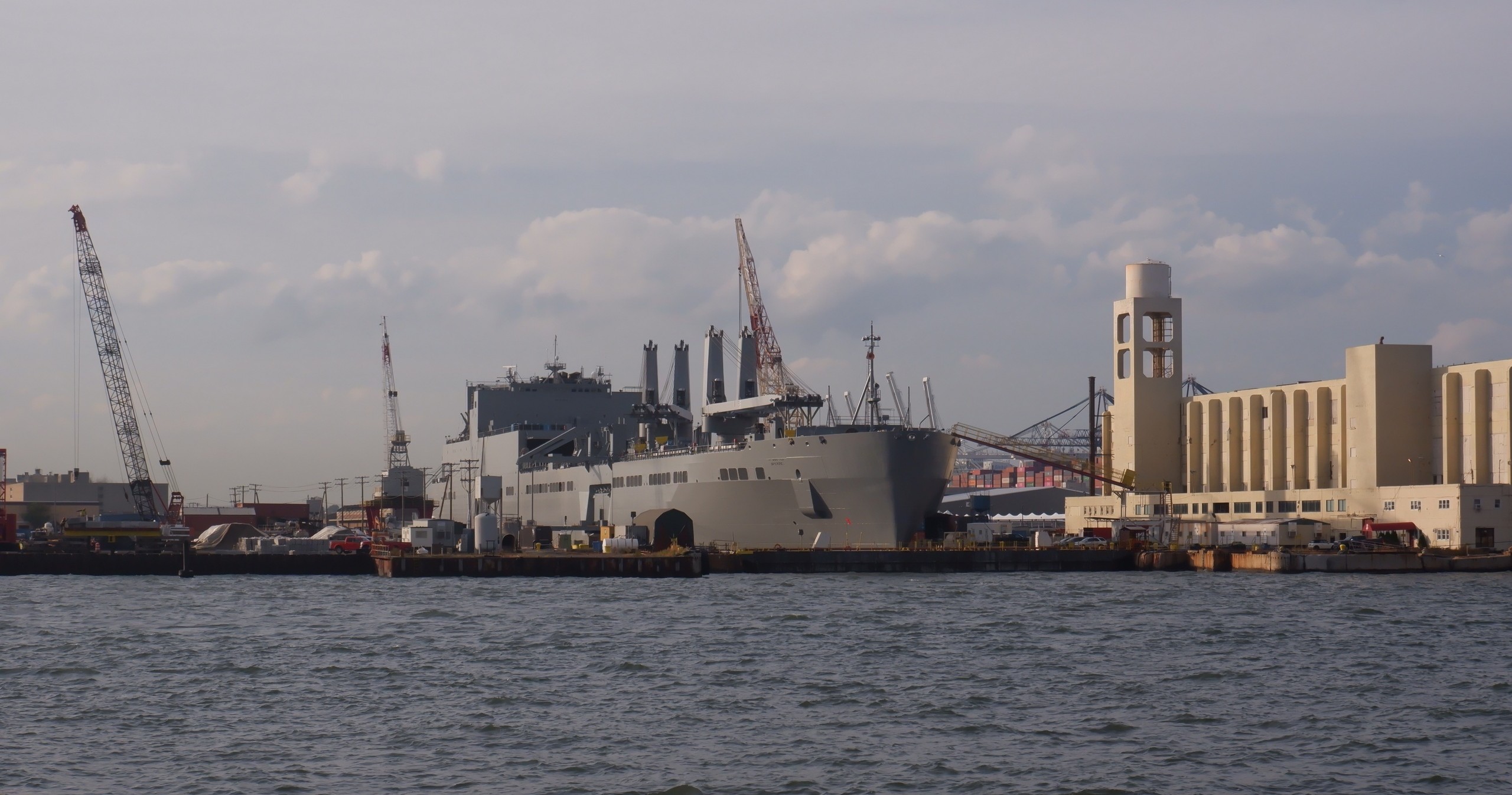 Large ship docked at an industrial port with cranes and warehouses.